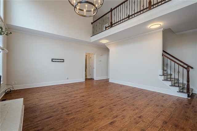 unfurnished living room with an inviting chandelier, dark hardwood / wood-style floors, and a high ceiling