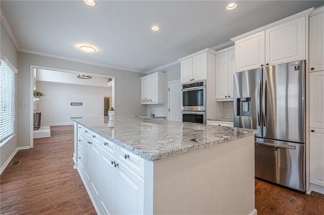 kitchen with white cabinetry, appliances with stainless steel finishes, a center island, and light stone counters