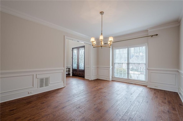 empty room featuring french doors, ornamental molding, dark hardwood / wood-style floors, and a chandelier