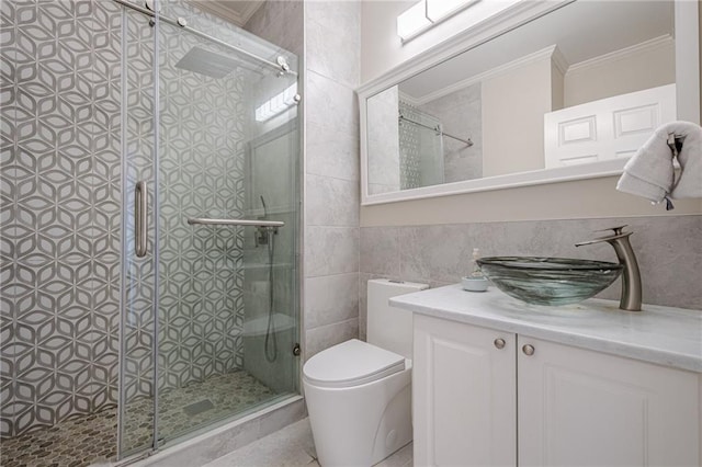 bathroom with tile walls, ornamental molding, vanity, toilet, and a shower with door