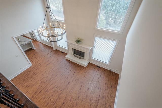 unfurnished living room featuring hardwood / wood-style flooring, a towering ceiling, and a chandelier