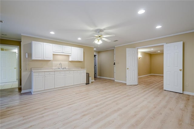 kitchen featuring sink, crown molding, light wood-type flooring, ceiling fan, and white cabinets