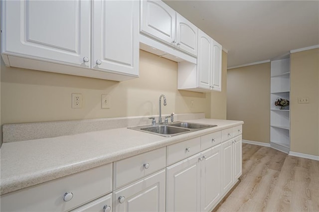 kitchen featuring sink, crown molding, white cabinets, and light wood-type flooring