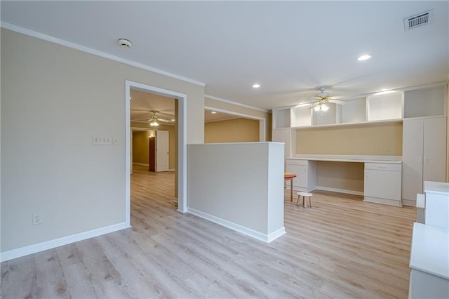 spare room featuring crown molding, ceiling fan, built in desk, and light hardwood / wood-style flooring