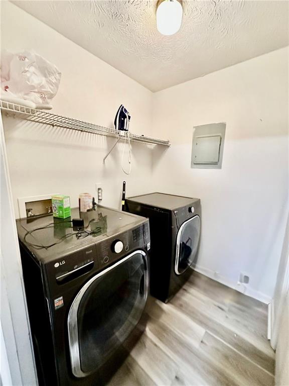 washroom with hardwood / wood-style floors, washing machine and clothes dryer, and a textured ceiling