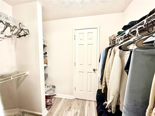 walk in closet with light hardwood / wood-style floors