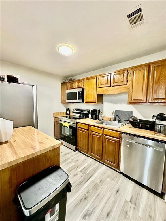 kitchen featuring appliances with stainless steel finishes, sink, and light hardwood / wood-style floors