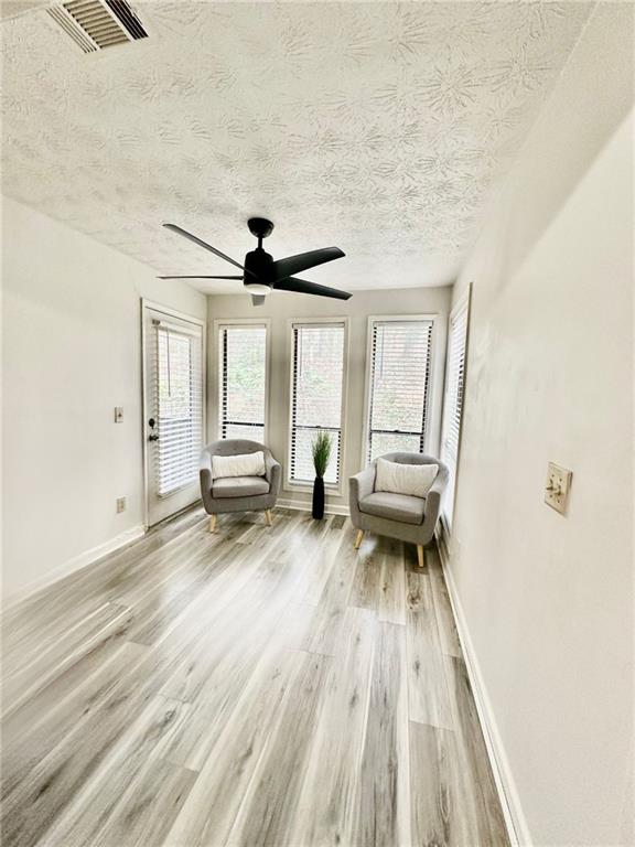 unfurnished room with ceiling fan, a textured ceiling, and light wood-type flooring