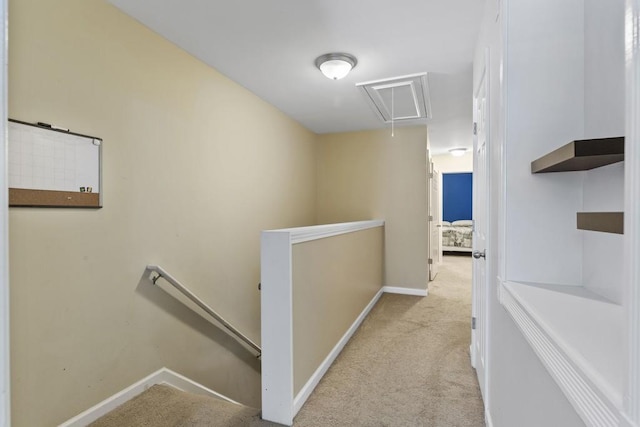 hallway featuring attic access, an upstairs landing, carpet floors, and baseboards