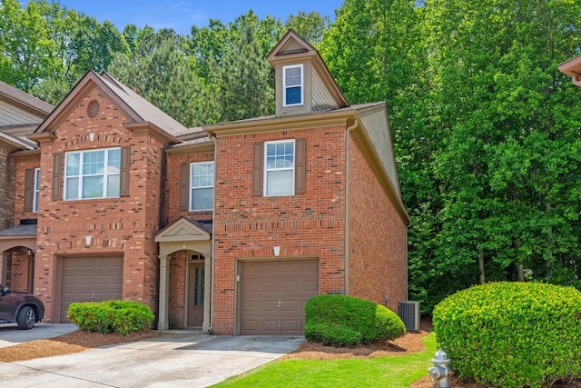 view of front of home featuring driveway, an attached garage, brick siding, and central air condition unit