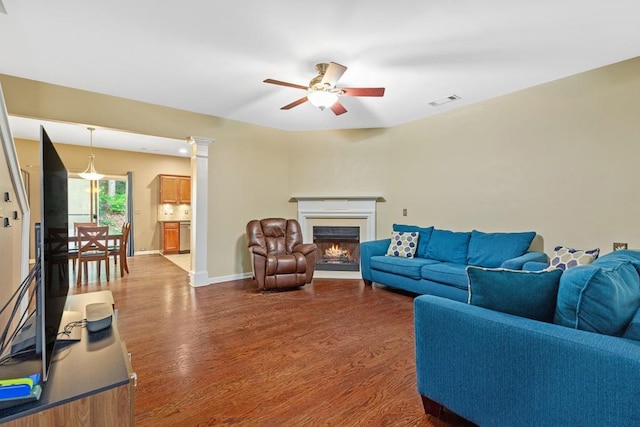 living room with a ceiling fan, dark wood-style floors, a warm lit fireplace, and baseboards
