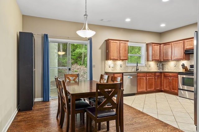 kitchen with stainless steel appliances, backsplash, dark countertops, a sink, and recessed lighting