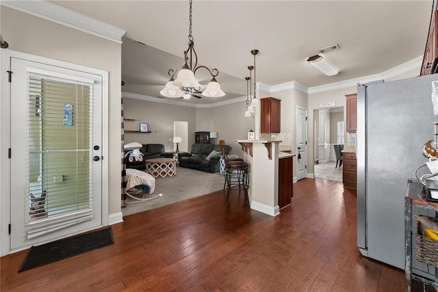 kitchen featuring visible vents, freestanding refrigerator, open floor plan, a kitchen breakfast bar, and a notable chandelier