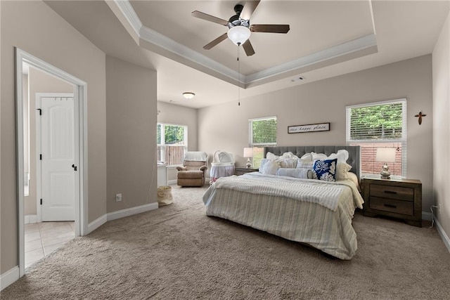 bedroom with crown molding, baseboards, a tray ceiling, and carpet flooring