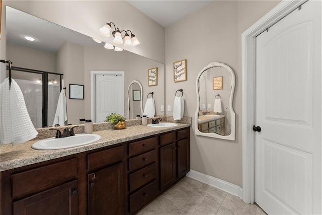 full bath featuring double vanity, baseboards, a sink, and a stall shower