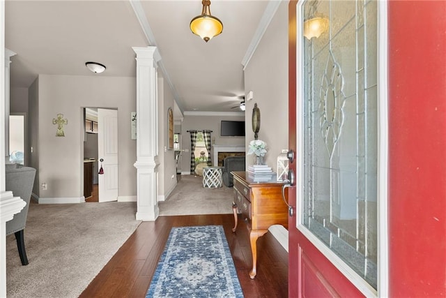 foyer entrance with ornamental molding, a fireplace, baseboards, ceiling fan, and ornate columns