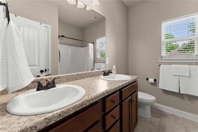 full bathroom featuring double vanity, toilet, tile patterned floors, and a sink