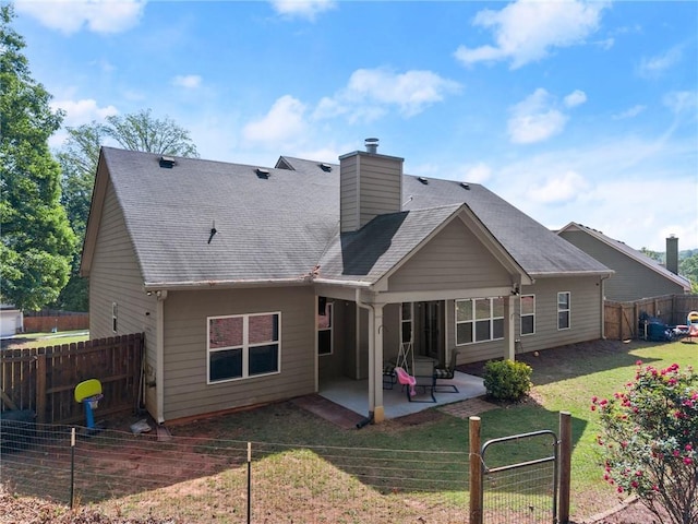rear view of house featuring a chimney, a patio area, a fenced backyard, a yard, and a shingled roof
