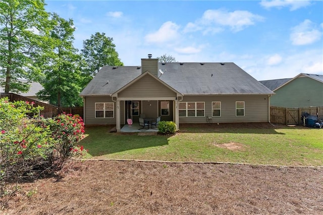 back of property featuring a lawn, a fenced backyard, a patio area, and a chimney
