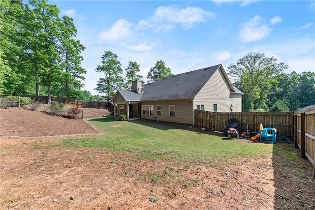 rear view of house featuring a lawn, a fenced backyard, and a chimney