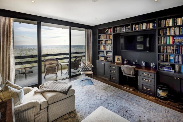 office with built in desk, built in shelves, dark hardwood / wood-style flooring, and a healthy amount of sunlight