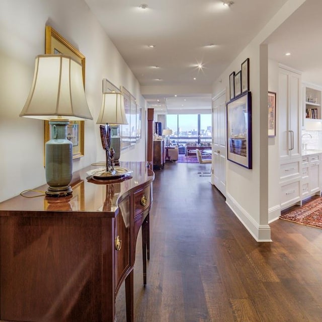 hall with dark wood-type flooring, floor to ceiling windows, and sink