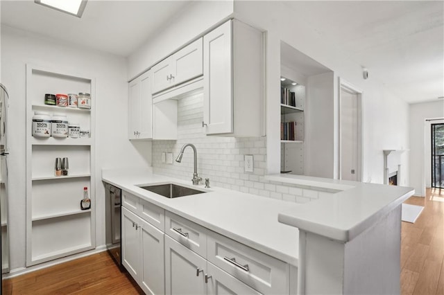 kitchen with sink, dishwasher, dark hardwood / wood-style floors, white cabinets, and kitchen peninsula