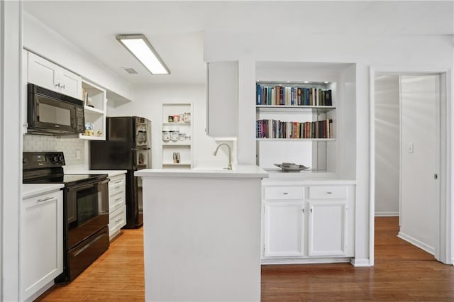 kitchen with hardwood / wood-style floors, white cabinets, backsplash, and black appliances