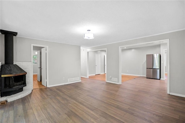 2215 Springdale Rd SW, Atlanta, GA 30315 - unfurnished living room featuring wood finished floors, ornamental molding, baseboards, a textured ceiling, and a wood stove