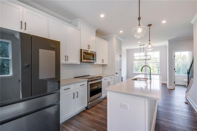 kitchen featuring sink, hanging light fixtures, appliances with stainless steel finishes, an island with sink, and white cabinets