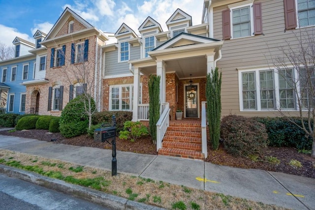 multi unit property featuring covered porch and brick siding