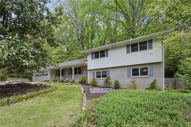 tri-level home with brick siding, fence, a front lawn, and a garage