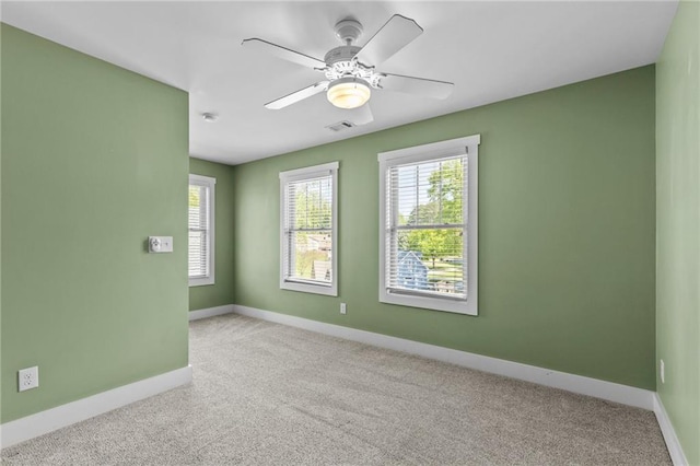 carpeted spare room featuring baseboards, a ceiling fan, and visible vents