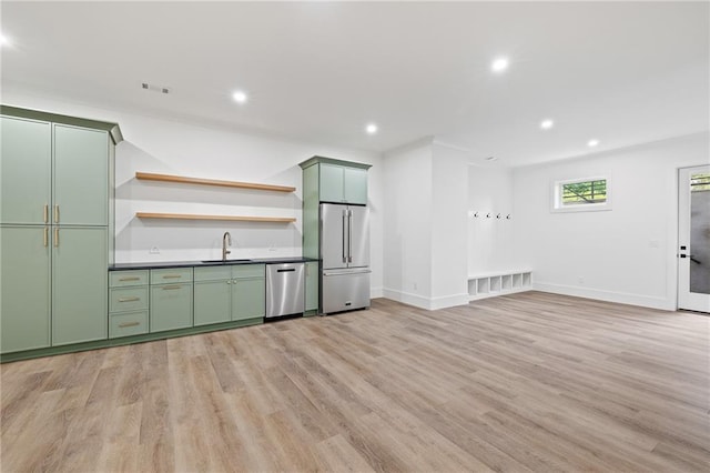 kitchen featuring appliances with stainless steel finishes, sink, light hardwood / wood-style floors, and green cabinetry