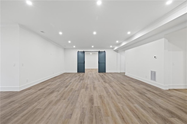 unfurnished living room featuring light hardwood / wood-style floors and a barn door