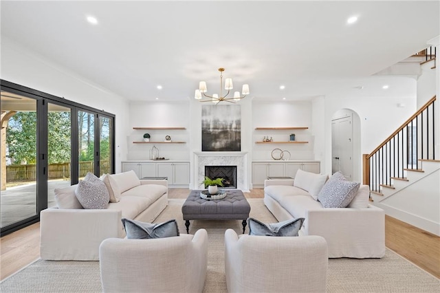 living room featuring sink, a fireplace, a chandelier, and light wood-type flooring