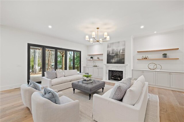 living room featuring a notable chandelier, a fireplace, french doors, and light wood-type flooring