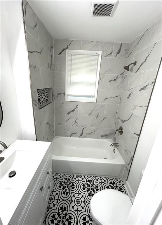 full bathroom featuring tiled shower / bath combo, vanity, and toilet