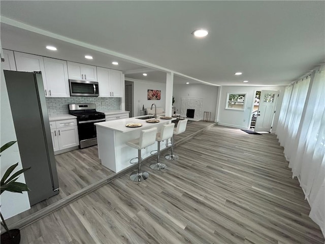 kitchen featuring sink, a center island with sink, a kitchen breakfast bar, stainless steel appliances, and white cabinets