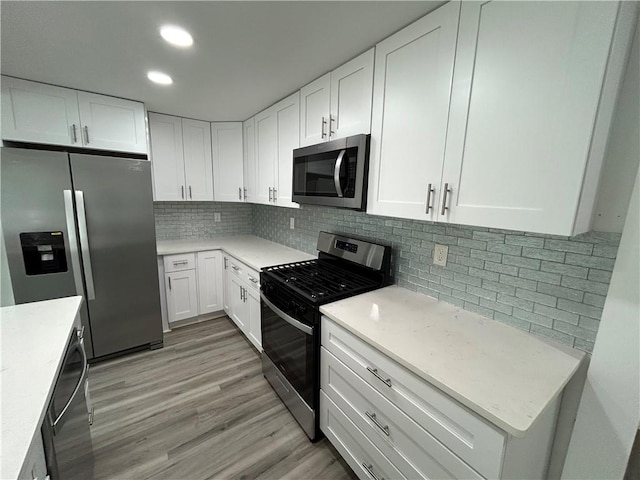 kitchen with decorative backsplash, light hardwood / wood-style flooring, white cabinets, and appliances with stainless steel finishes