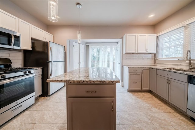 kitchen with tasteful backsplash, appliances with stainless steel finishes, sink, and white cabinets