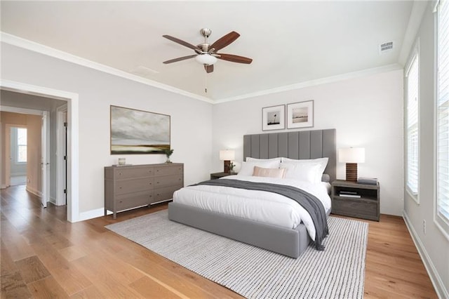 bedroom with visible vents, light wood-style flooring, ornamental molding, ceiling fan, and baseboards