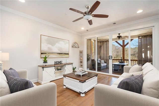 living area featuring visible vents, ornamental molding, light wood-style flooring, and baseboards