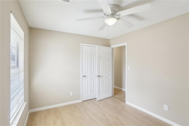 unfurnished bedroom with ceiling fan, a textured ceiling, light hardwood / wood-style floors, and a closet