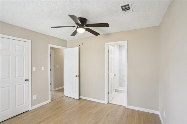 unfurnished bedroom featuring ceiling fan, a textured ceiling, light wood-type flooring, and ensuite bath