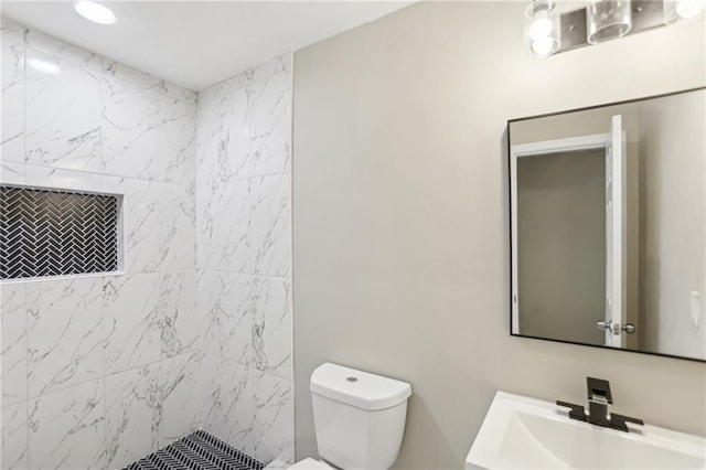 bathroom featuring vanity, toilet, and tiled shower