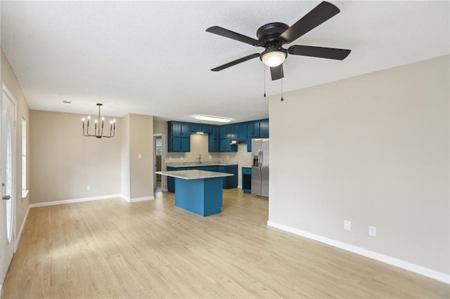 kitchen with blue cabinetry, a breakfast bar area, light wood-type flooring, stainless steel fridge, and a kitchen island