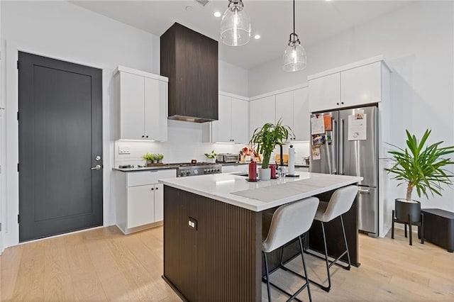 kitchen featuring pendant lighting, a center island, white cabinets, appliances with stainless steel finishes, and light hardwood / wood-style floors