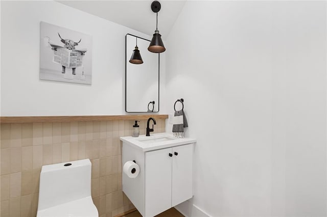 bathroom with vanity, toilet, and tile walls