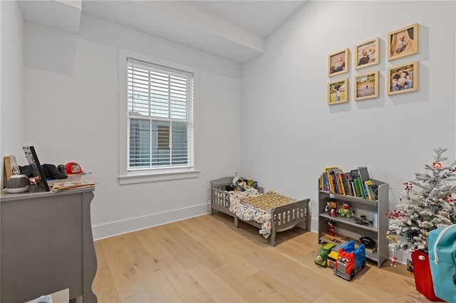 bedroom with hardwood / wood-style floors and a nursery area